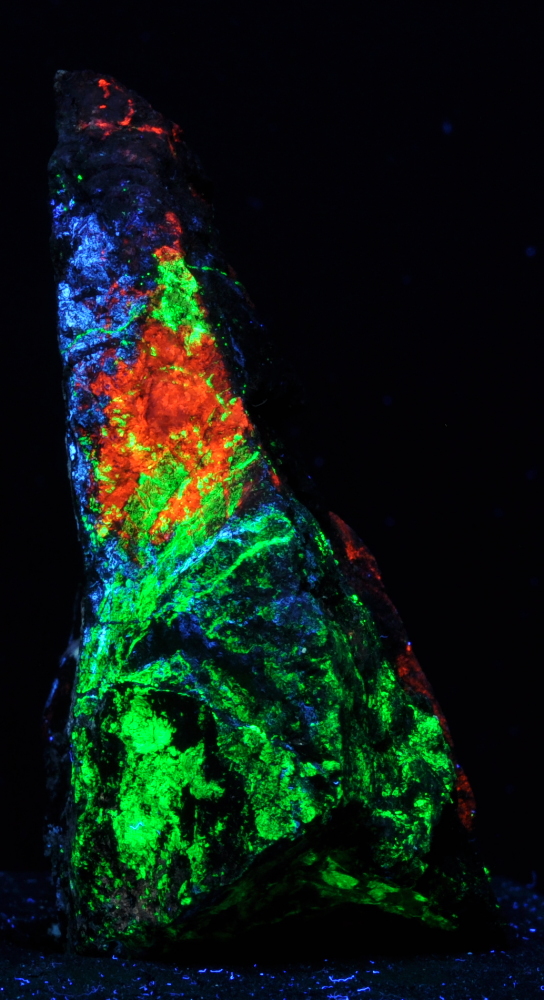 Red/orange calcite, green willemite, and blue/grey hydrozincite; shortwave; 10 cm