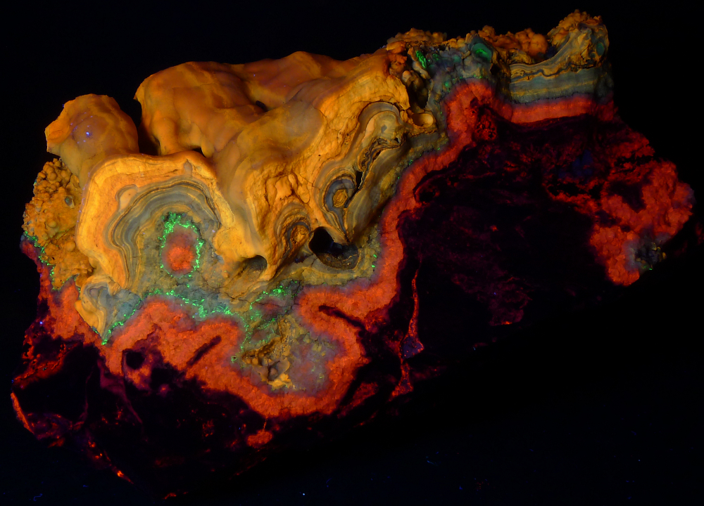 Dark limestone, orange calcite veins, yellow and gold travertine, and bright green opal; 33 cm