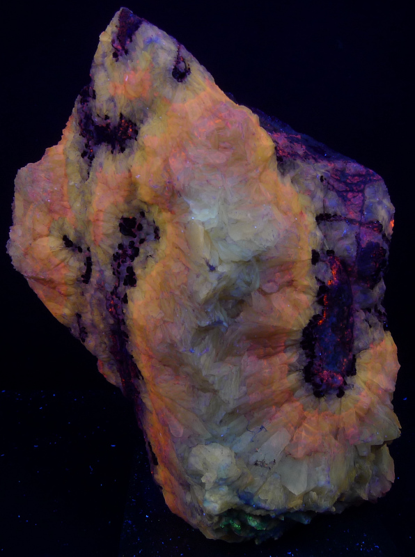 Orange, pink, and yellow calcite with manganese spheres on limestone; 15 cm