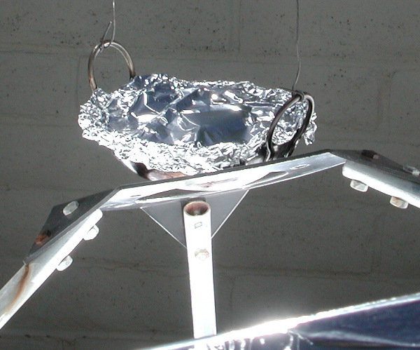 Foil covered lamb dish hanging over cooker